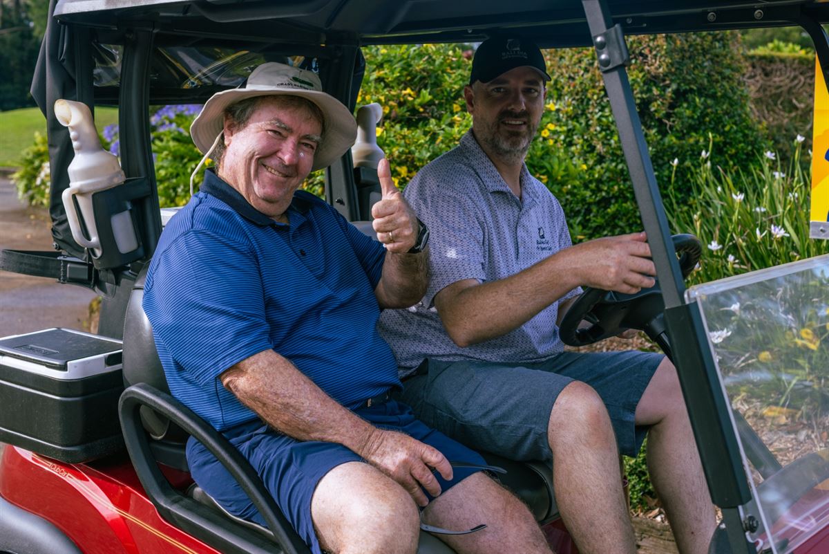 Two players sharing a laugh in a golf cart on the course